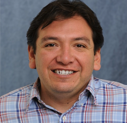 man in plaid shirt and dark hair smiling